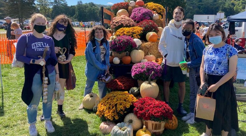 students at a fall festival with mums, and pumpkins and garlic in their hands